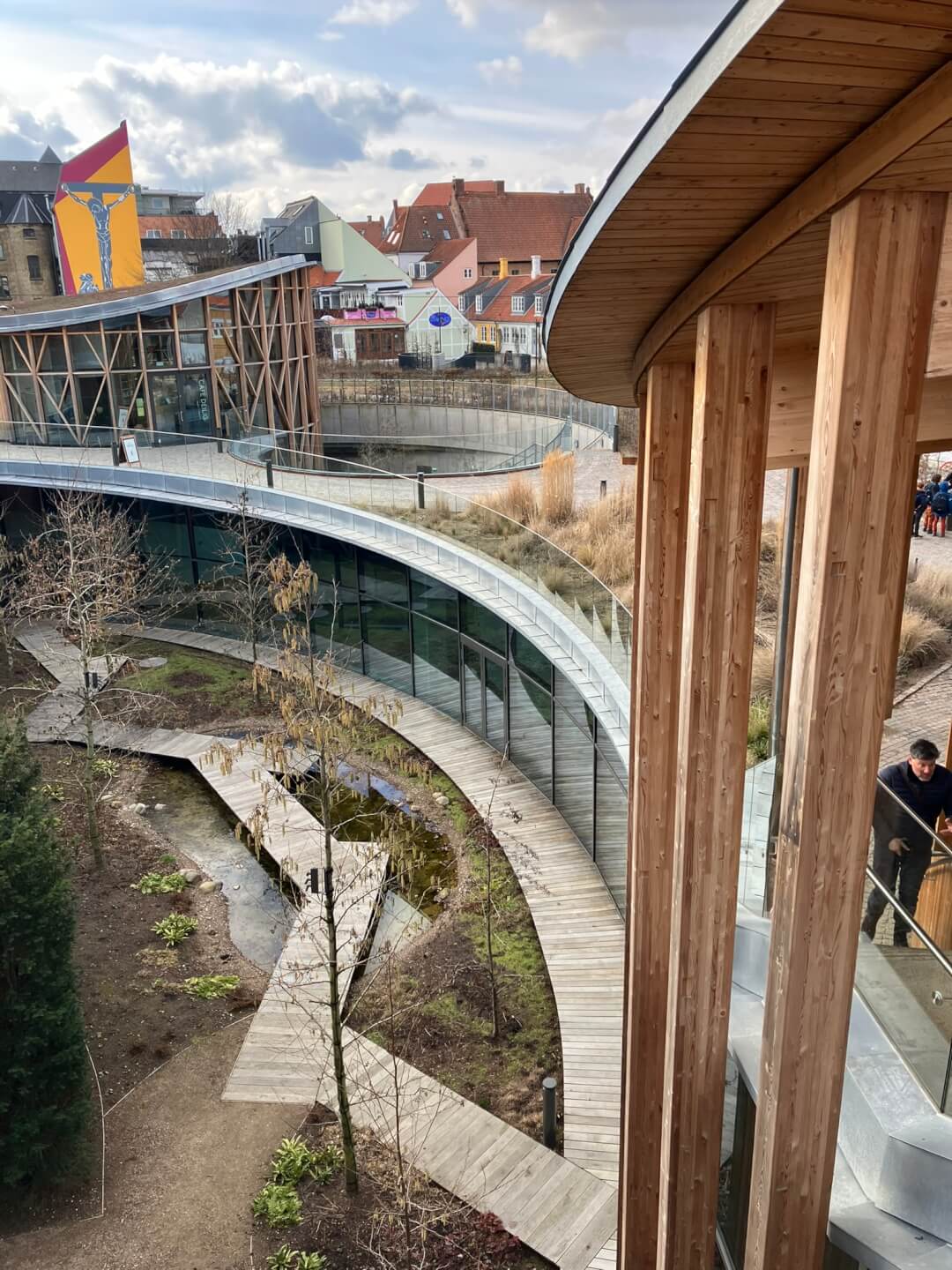 Modernes Bauprojekt mit geschwungenem Holz-Glas-Bau, bepflanztem Innenhof, nachhaltige Architektur